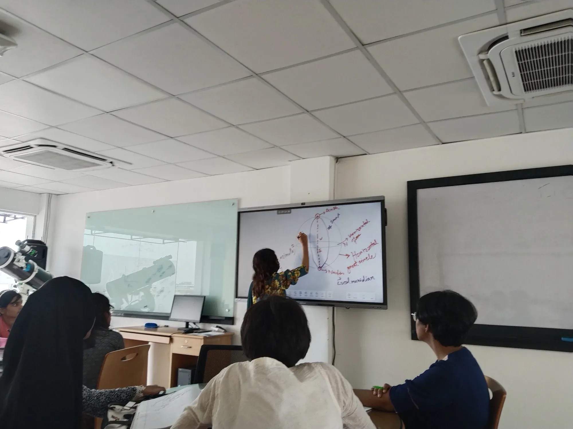 An instructor drawing a celestial sphere on the smartboard, labelled with zenith, nadir, azimuth, the horizontal great circle and the local meridian.