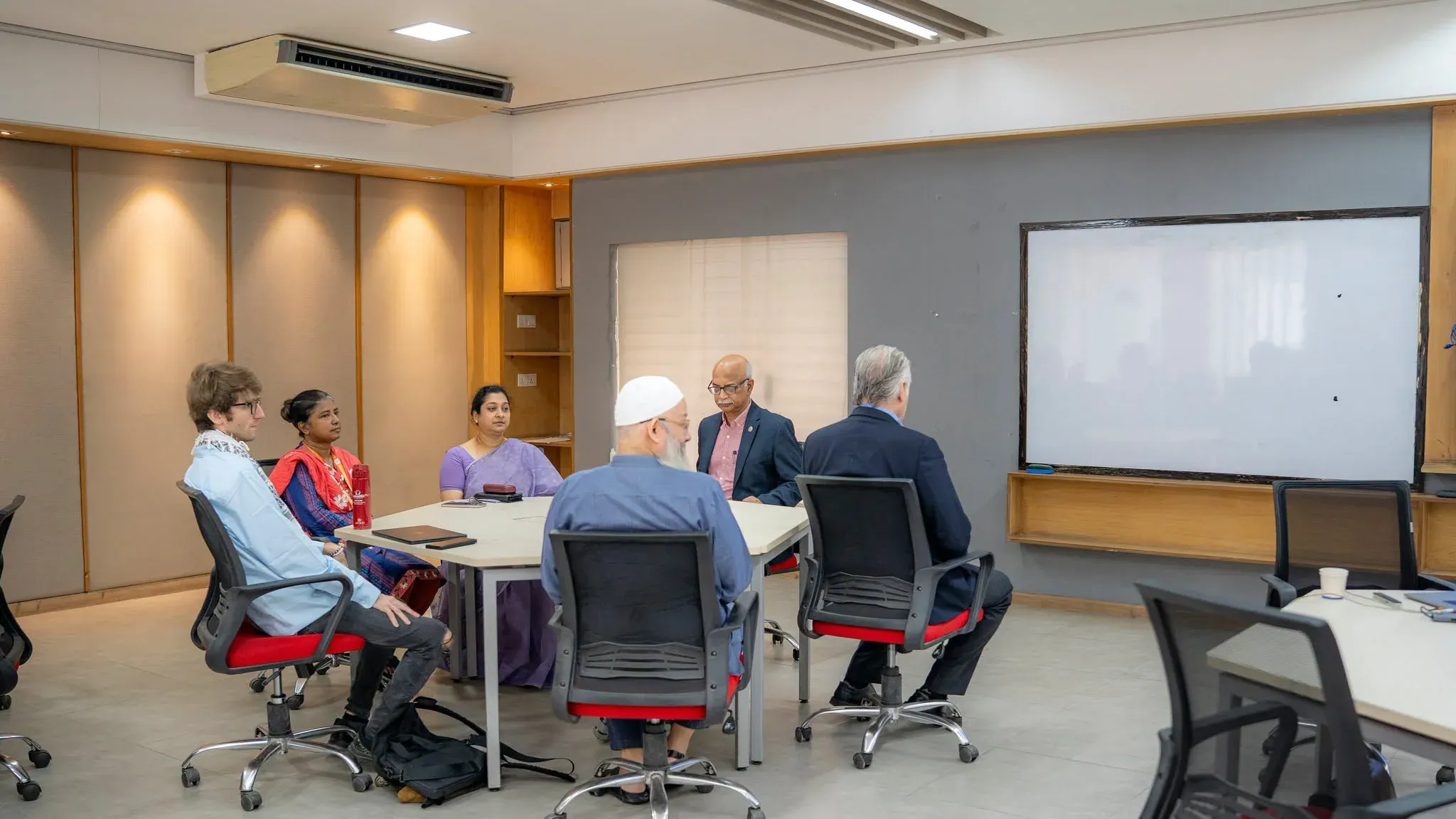The front table of the Digital Classroom seen head-on, with Dr. Andrew L. Miller at the far left in a scarf.