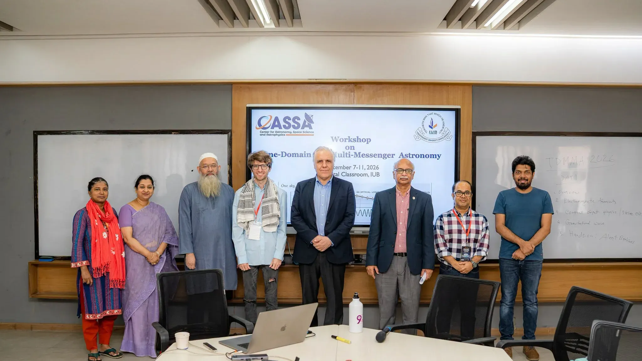IUB officials, CASSA members and visiting lecturer Dr. Andrew L. Miller stand in a line in front of the TDMMA 2026 title slide.