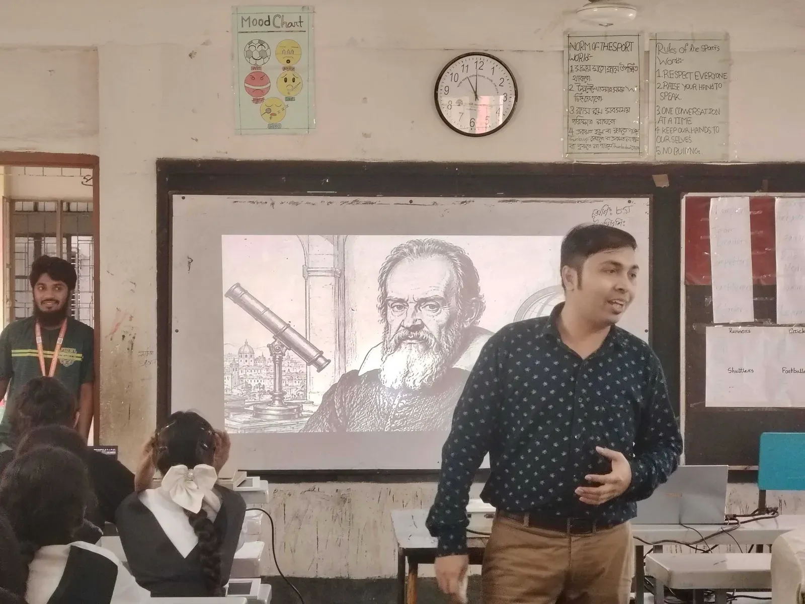 A volunteer leads the storytelling session in front of a slide showing Galileo Galilei and his telescope.