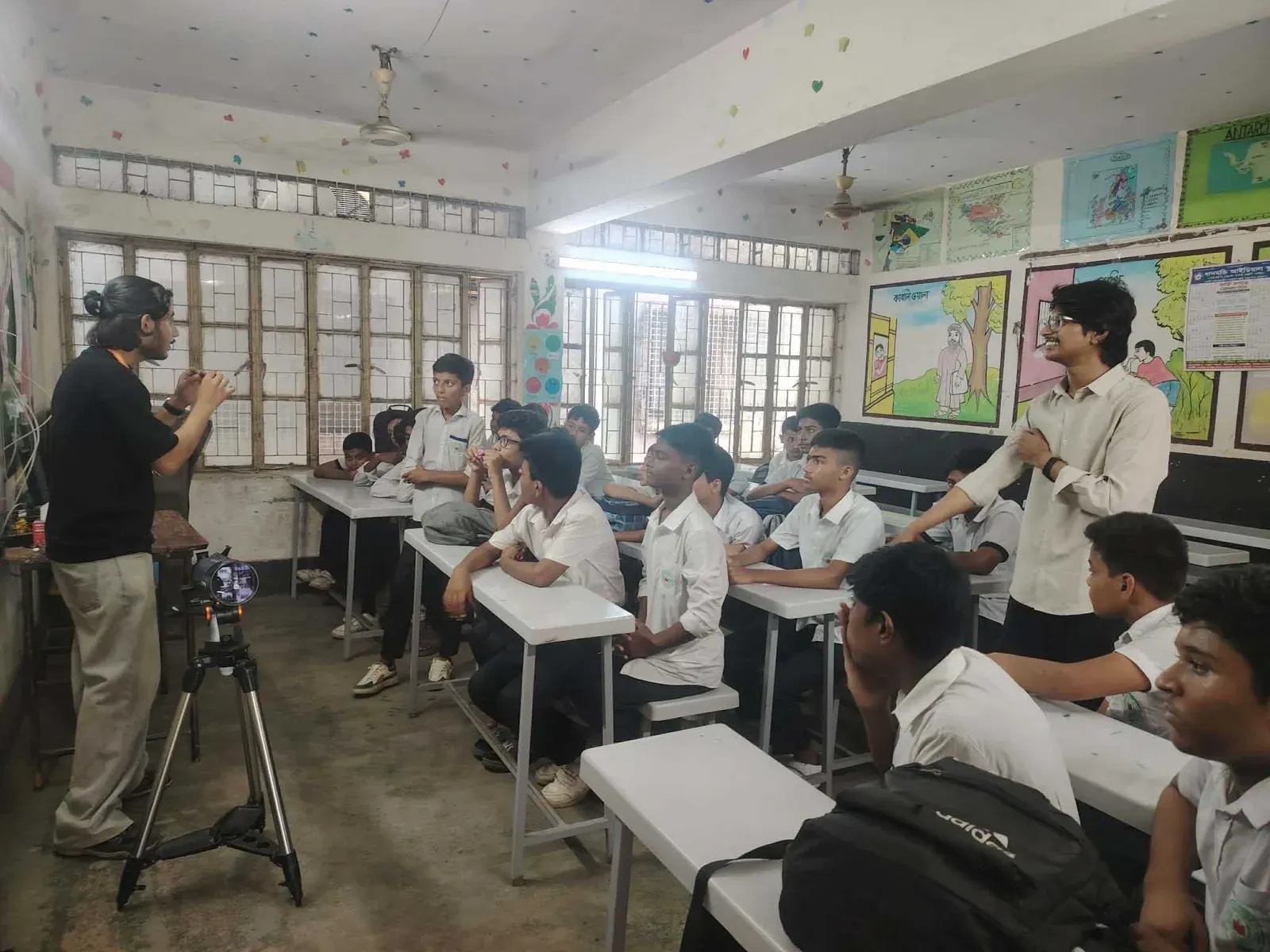 A volunteer explains how a telescope works to a classroom of seated students.