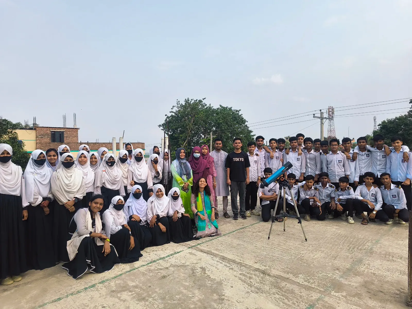 Durbin volunteers and the students of Nagarbari Maritime School and College gathered around a telescope for a group photo.