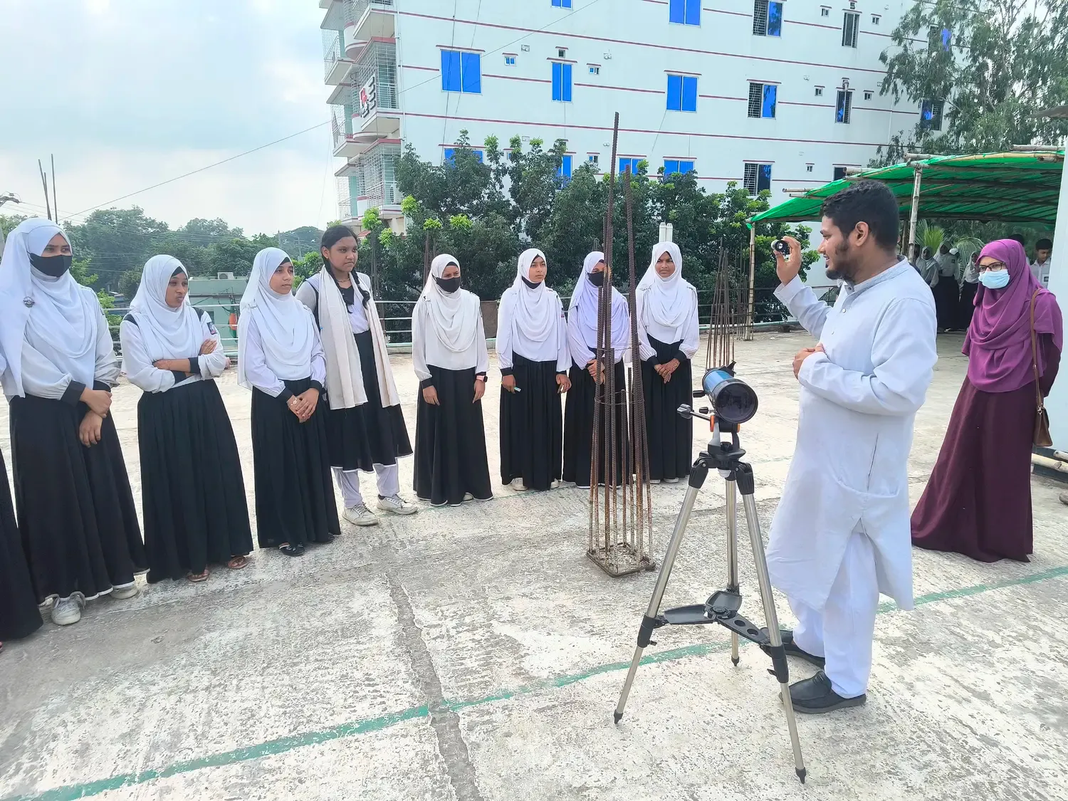 A volunteer demonstrating the telescope to a group of students outdoors.