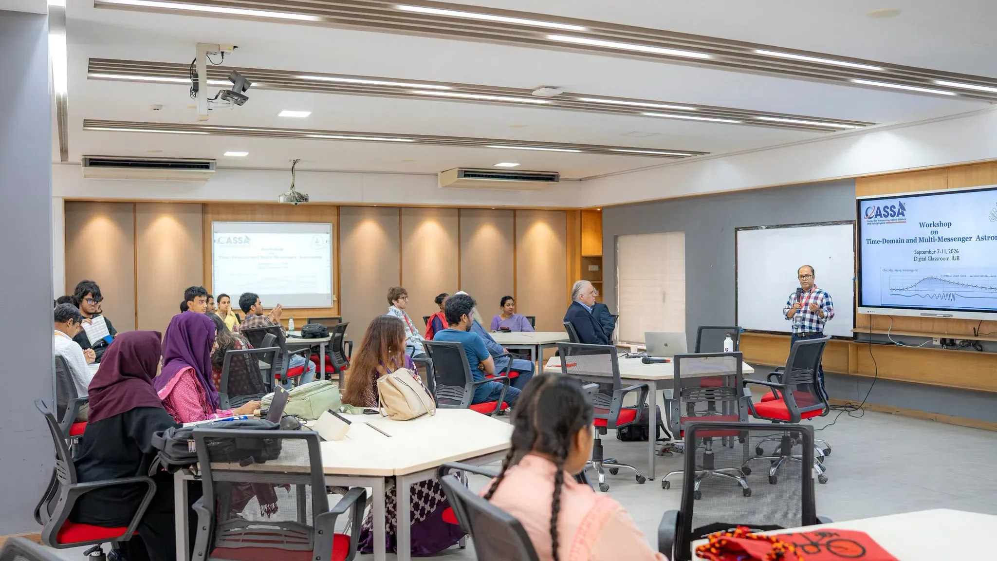Workshop participants seated at tables in the Digital Classroom, facing the screen.