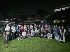 Participants and Durbin volunteers gathered on the TSC lawn at night, several holding framed astrophotographs, with a telescope at the left of the frame.