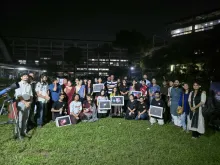 Participants and Durbin volunteers gathered on the TSC lawn at night, several holding framed astrophotographs, with a telescope at the left of the frame.