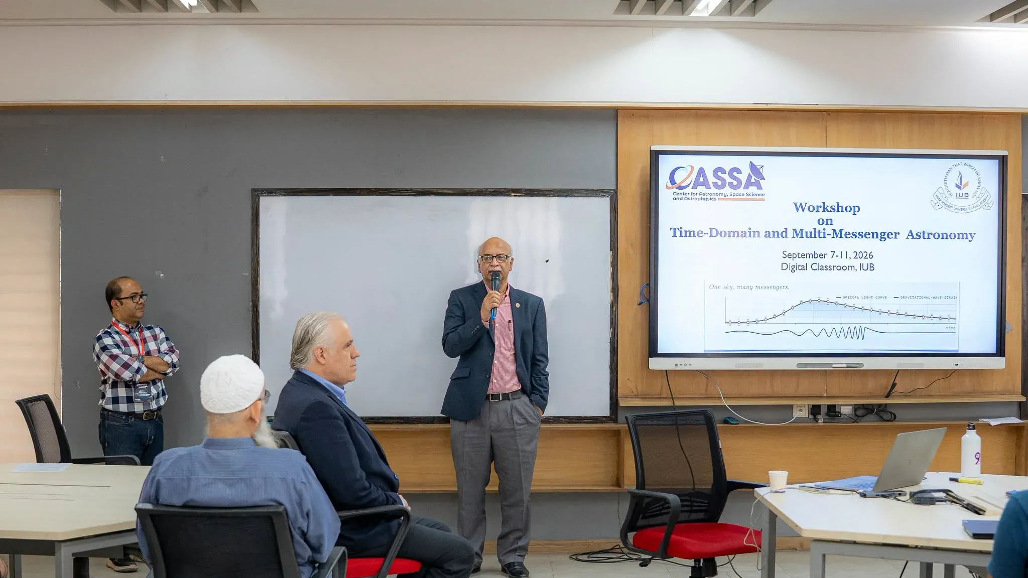 IUB Vice Chancellor Prof. Dr. M. Tamim speaks into a microphone beside the TDMMA 2026 title slide in the Digital Classroom.